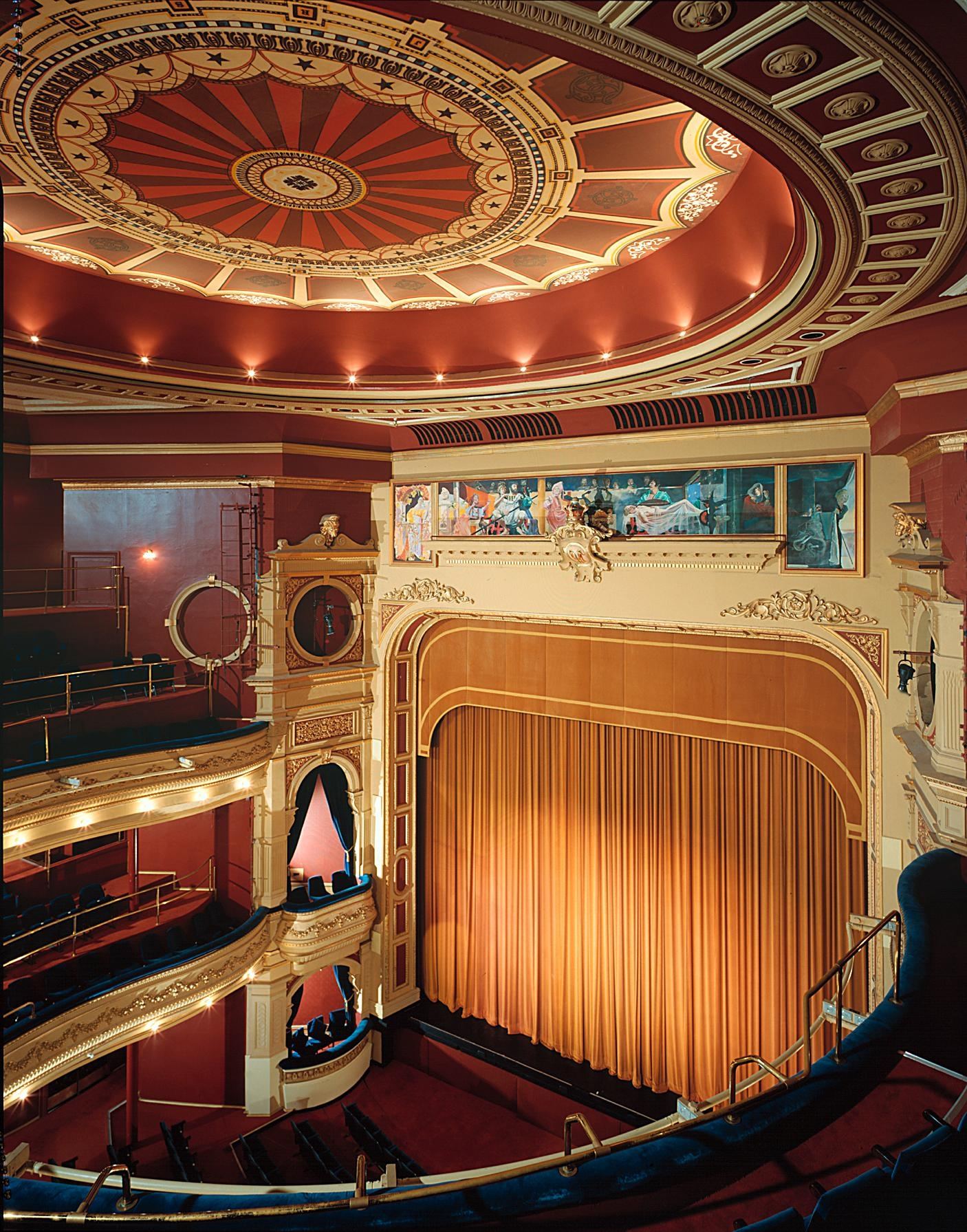 A red theatre curtain under a painted dome